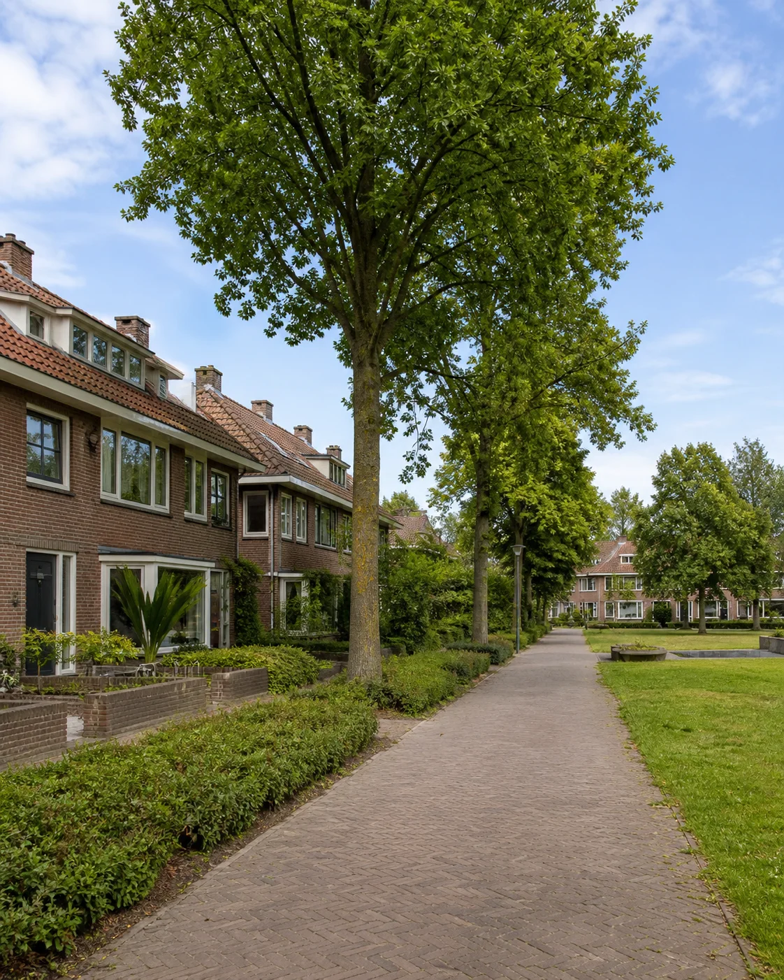 Groene woonstraat met bakstenen gezinswoningen en wandelpad in Tempel, Eindhoven